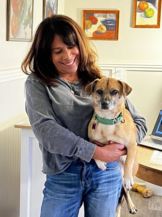 woman smiling standing holding a dog